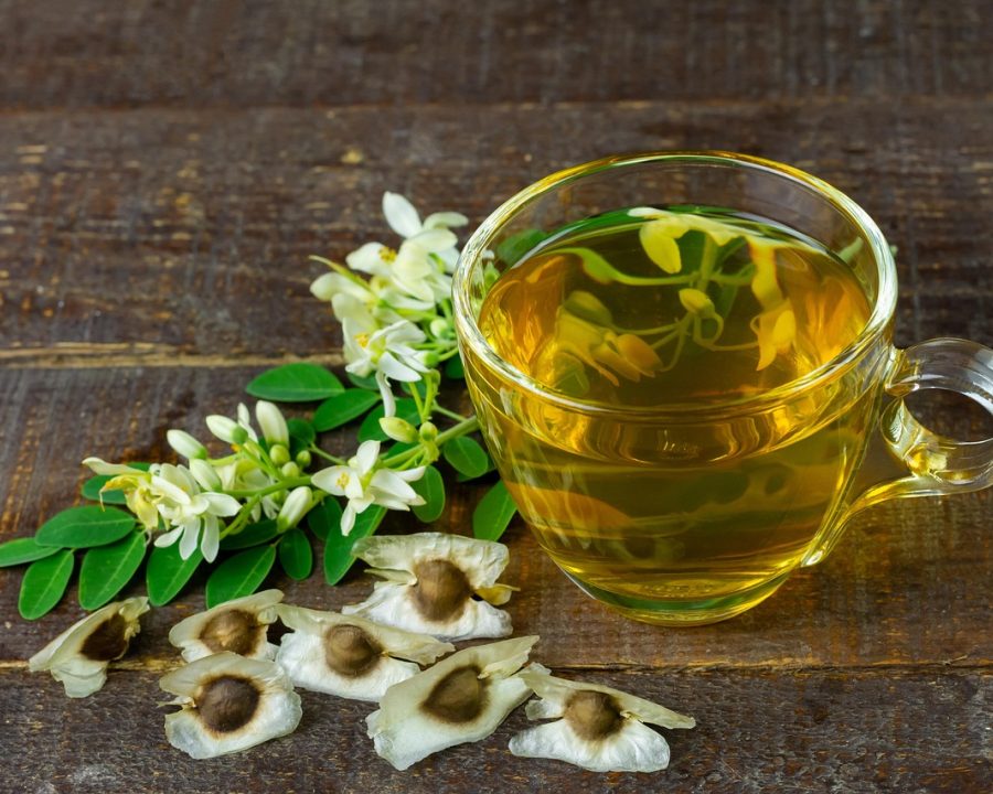 夜间书桌上摊开的纸质时间表、一支笔和半杯凉掉的茶，暖黄台灯照着被勾过的日程格子